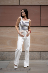 a lady in a striped tank top and a pair of white jeans